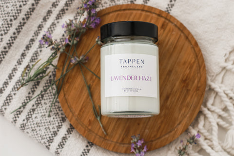 Lavender Haze Tappen Apothecary candle on a wooden board with lavender petals around it