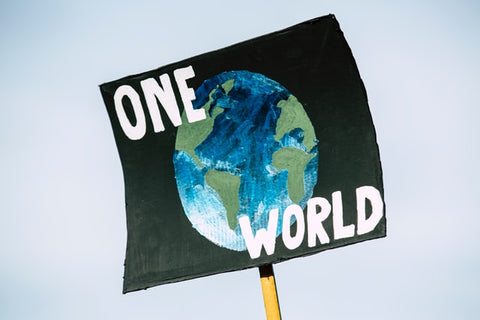 Black flag with an earth painting and the letters "One World". One world, Live sustainably, live slowly.