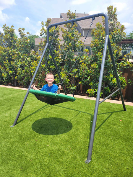 A young boy on a round swing attached to a single swing set.