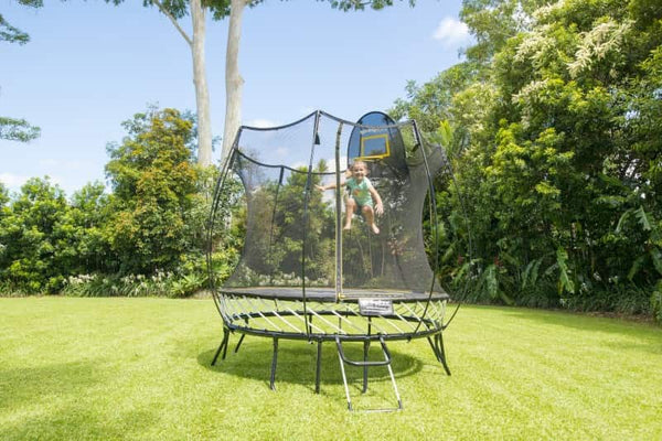 Little kid jumping on a Springfree Compact Oval Trampoline.