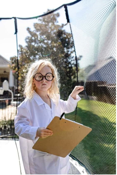 A little girl dressed as a doctor holding the Springfree Trampoline net.