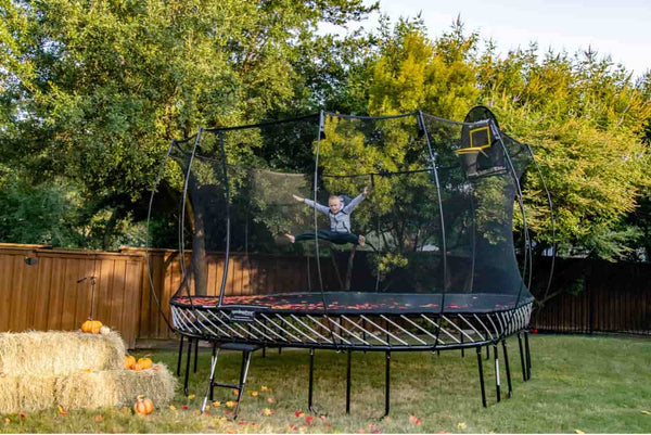 A kid jumping on a Springfree Trampoline with fake leaves on it.