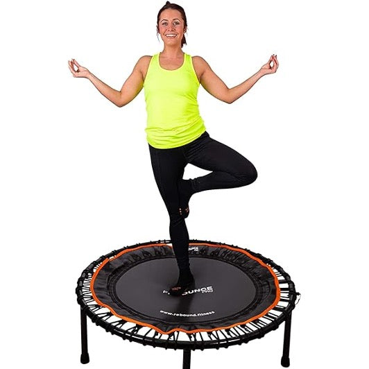 A woman standing with a pose on a Rebounder Trampoline.