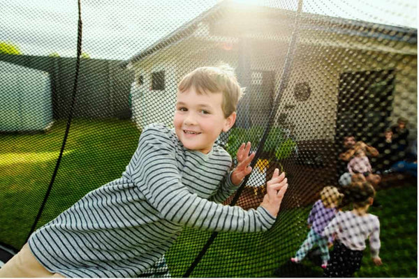 A little boy safely leaning on the Springfree Trampoline net.