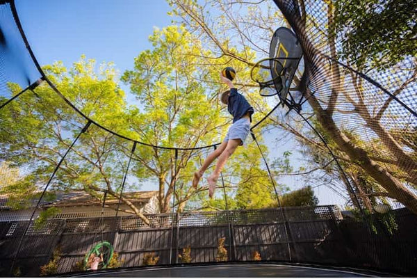 A boy about to dunk on a Springfree Trampoline Hoop.