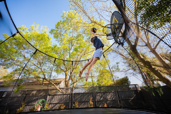 Boy dunking on Springfree Trampoline Basketball Hoop.