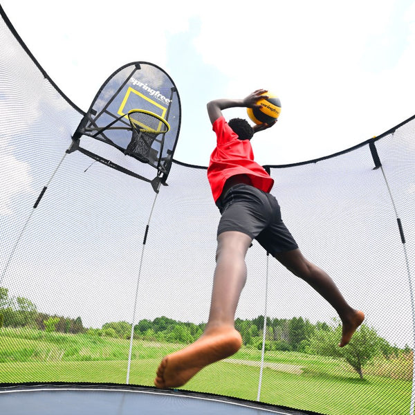 A child dunking on a Springfree Trampoline Hoop.