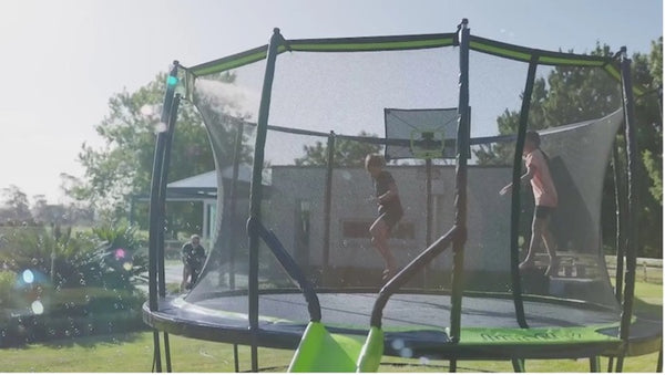 Two kids jumping on a Jumpflex Trampoline with a slide and water.