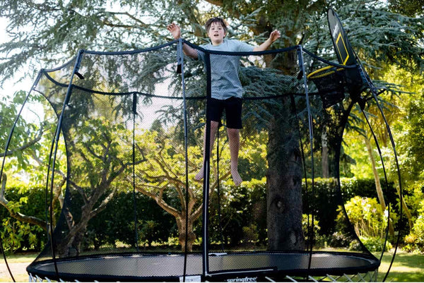 A kid jumping high in the air on a Springfree Trampoline.