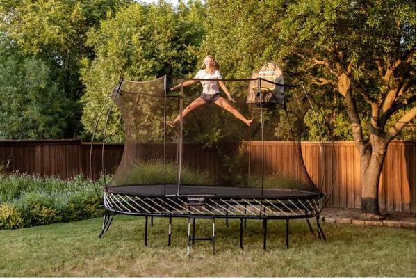 An adult jumping in mid-air on a Springfree Trampoline.