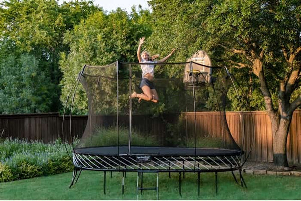 A woman happily jumping in mid-air on a Springfree Trampoline.