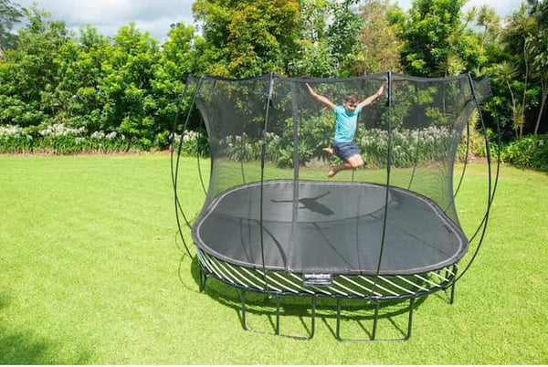 A kid in a blue shirt jumping on a Springfree Trampoline.