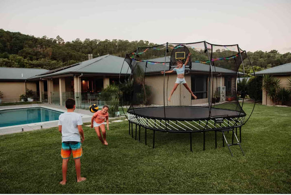 Kids playing on and around a Springfree Trampoline.