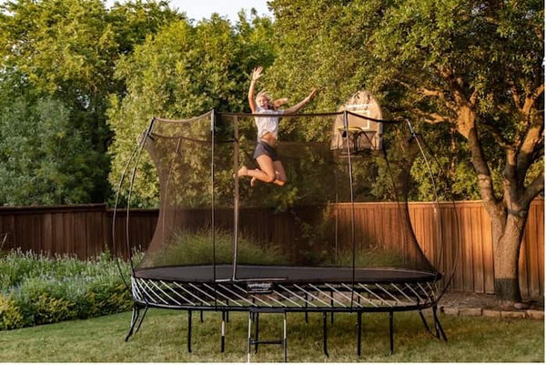 A women jumping in mid-air on a Springfree Trampoline.