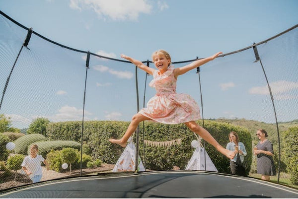 A girl smiling while jumping in the air on a Springfree Trampoline.