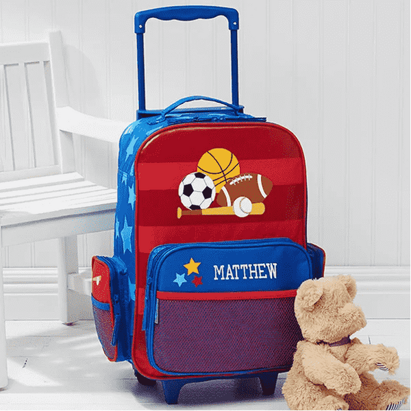 Custom sports-themed luggage with a teddy bear in front of it.