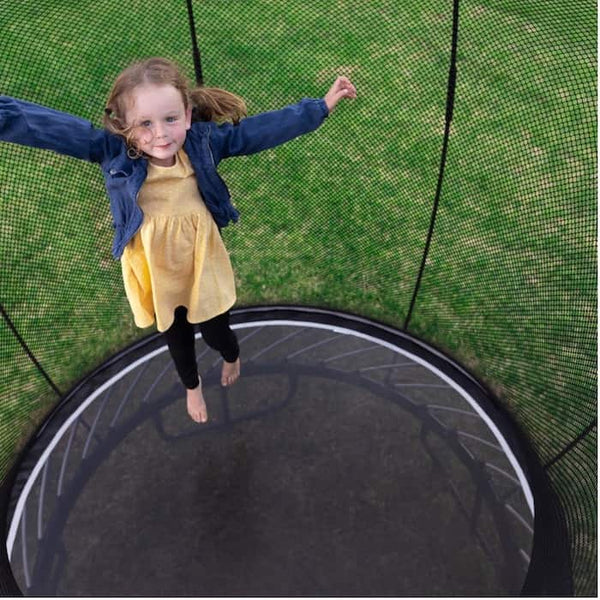 A little girl jumping on a trampoline mat.