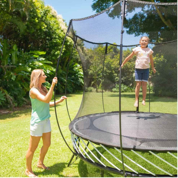 A mom watching her daughter jump on a Springfree Trampoline.