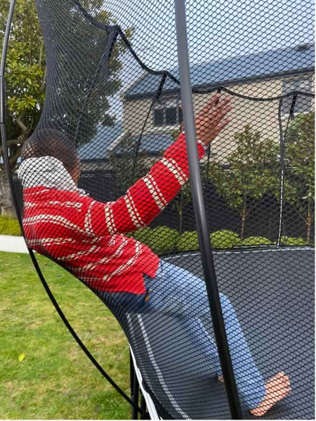 A child leaning safely against the Springfree Trampoline net.