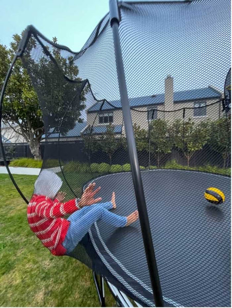 A child safely leaning against the Springfree Trampoline net.