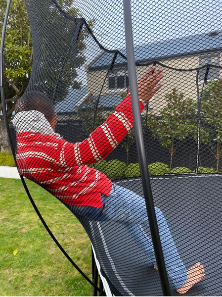 A child safely leaning against the Springfree Trampoline net.