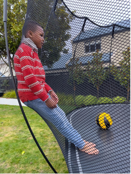A child safely leaning against the Springfree Trampoline net.