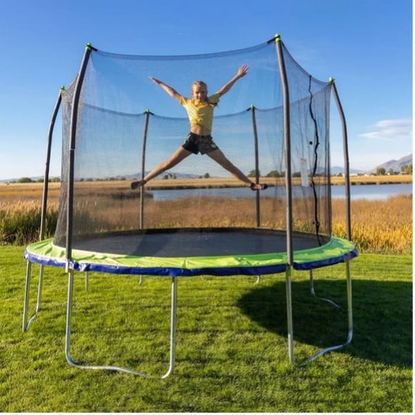 A little girl doing a star jump in mid-air on a trampoline.
