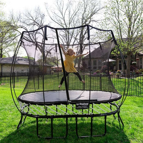 A little girl in a yellow shirt jumping on a Springfree Trampoline.