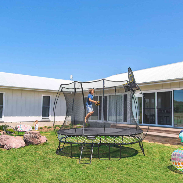 A child starting to dunk on the Springfree Trampoline Basketball Hoop.