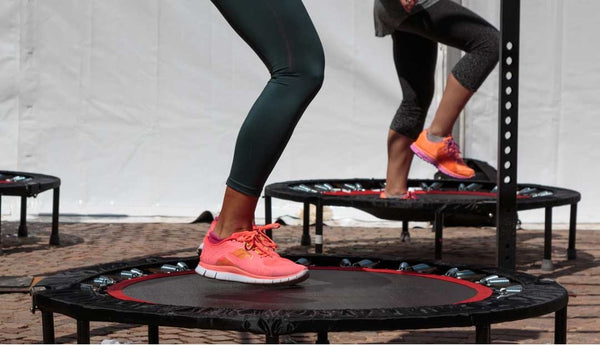 Multiple people jumping on rebounder trampolines.