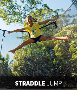 A child doing a straddle jump on a trampoline.