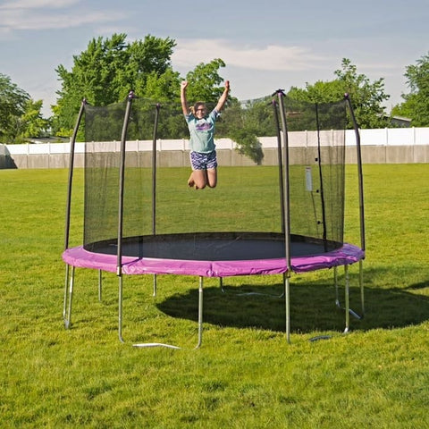 A girl jumping on a pink trampoline.
