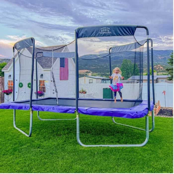 A little girl jumping on a Skywalker Trampoline with an American flag on it.