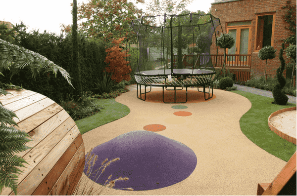 A small backyard with colored circles leading to a Springfree Trampoline.