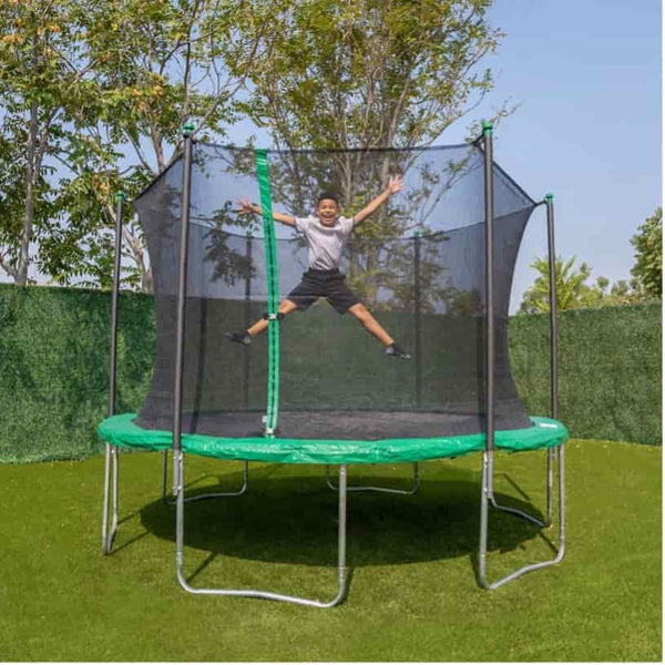A kid jumping on a spring trampoline with green safety padding.