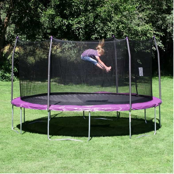 A girl jumping in mid-air touching her toes on a trampoline with pink spring padding.