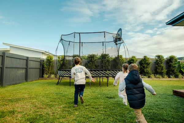 Three kids running to a Springfree Trampoline.