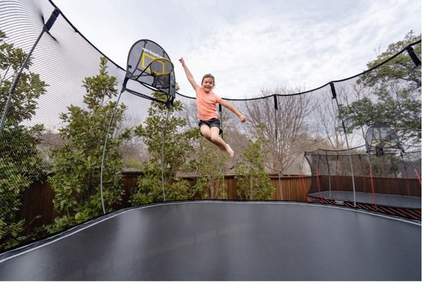 A girl jumping in mid-air on a Springfree Trampoline.