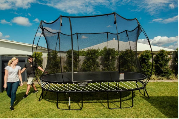 A man and a woman walking around a fully assembled Springfree Trampoline.