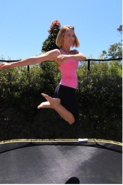 An athletic woman doing the Swivel Hip exercise on a Springfree Trampoline.