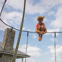 A young boy doing a Tuck Jump on a Springfree Trampoline.