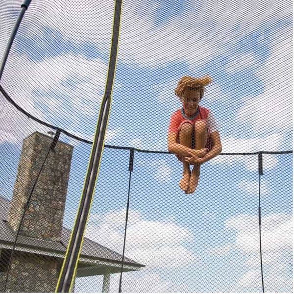 A child doing a tuck jump on a trampoline.