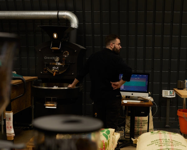 A coffee roasters at Hermanos handling green beans from the coffee supply chain