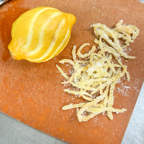 candied lemon peel and a stripped lemon on a cutting board