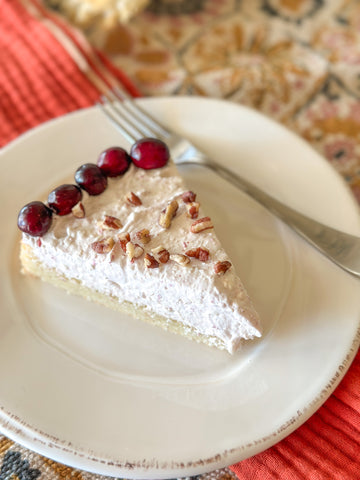 A slice of cranberry pecan fluff cookie pie on a white plate sitting on an orange napkin.