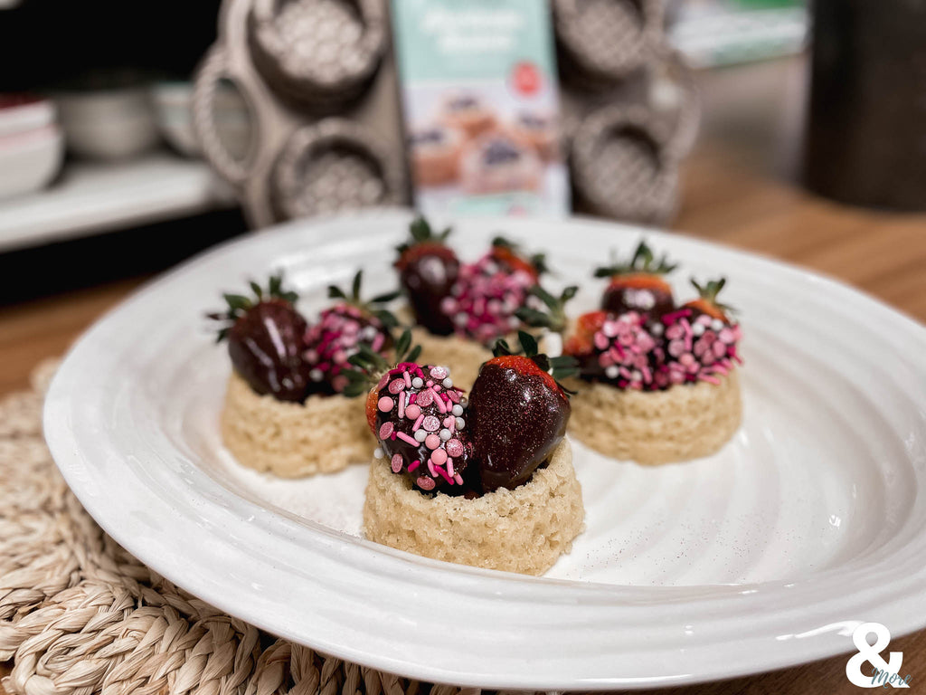 chocolate and sprinkle covered strawberries sit on a plate in front of a shortcake baskets baking pan