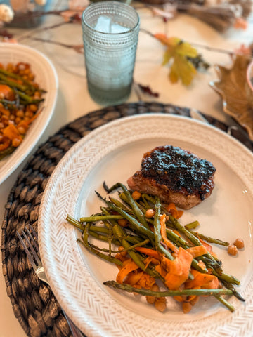 plated mesquite roasted vegetables with bacon + apple pork chops on a placemat.