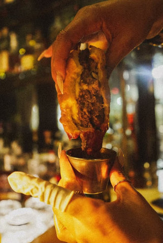 Cheeseburger being held and dipped into ketchup in a bar setting