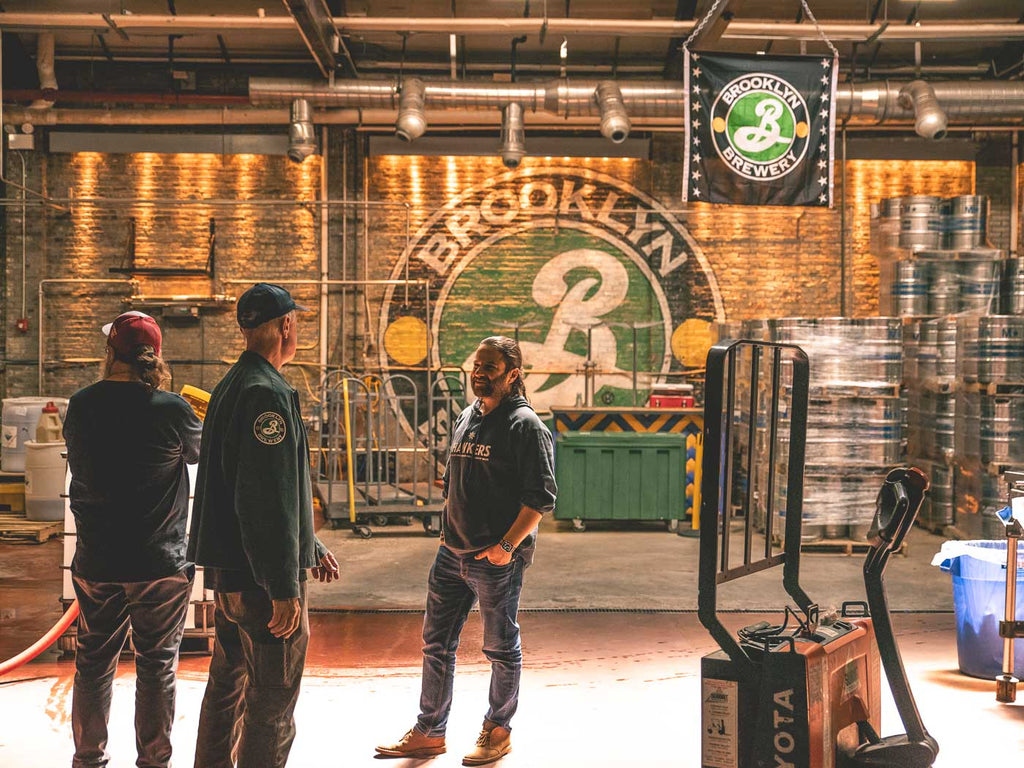 Alan from Brooklyn Brewery stands in the brewery chatting with Mazen and Alex