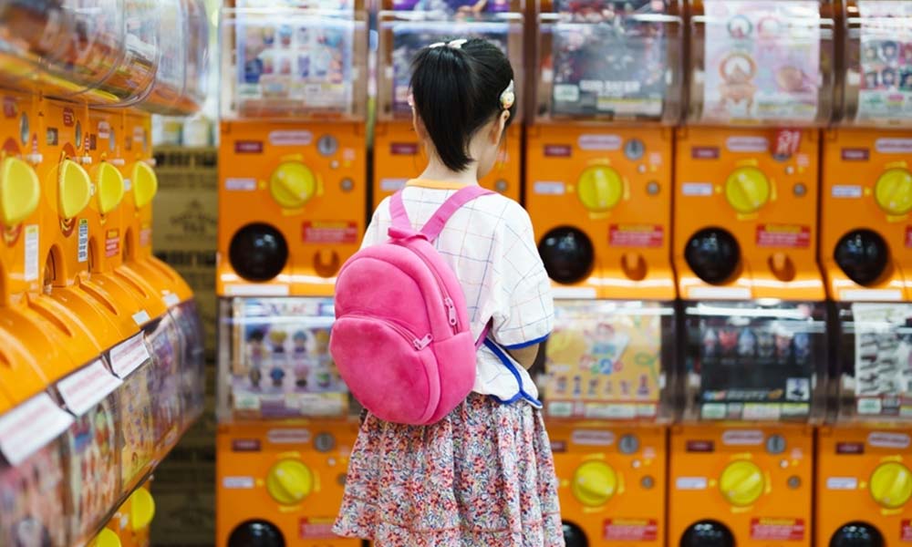 Une fillette au Japon devant une gashapon machine pour avoir une capsule avec une figurine